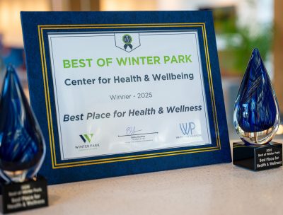 A framed certificate and two glass awards on a table display the Best of Winter Park 2025 award, recognizing the Center for Health & Wellbeing as one of the best places for health & wellness.