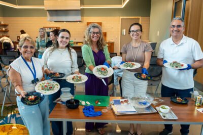 Group of people standing in front of nutrition theater, smiling with plant based meal on plates.