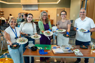 Group of people standing in front of nutrition theater, smiling with plant based meal on plates.
